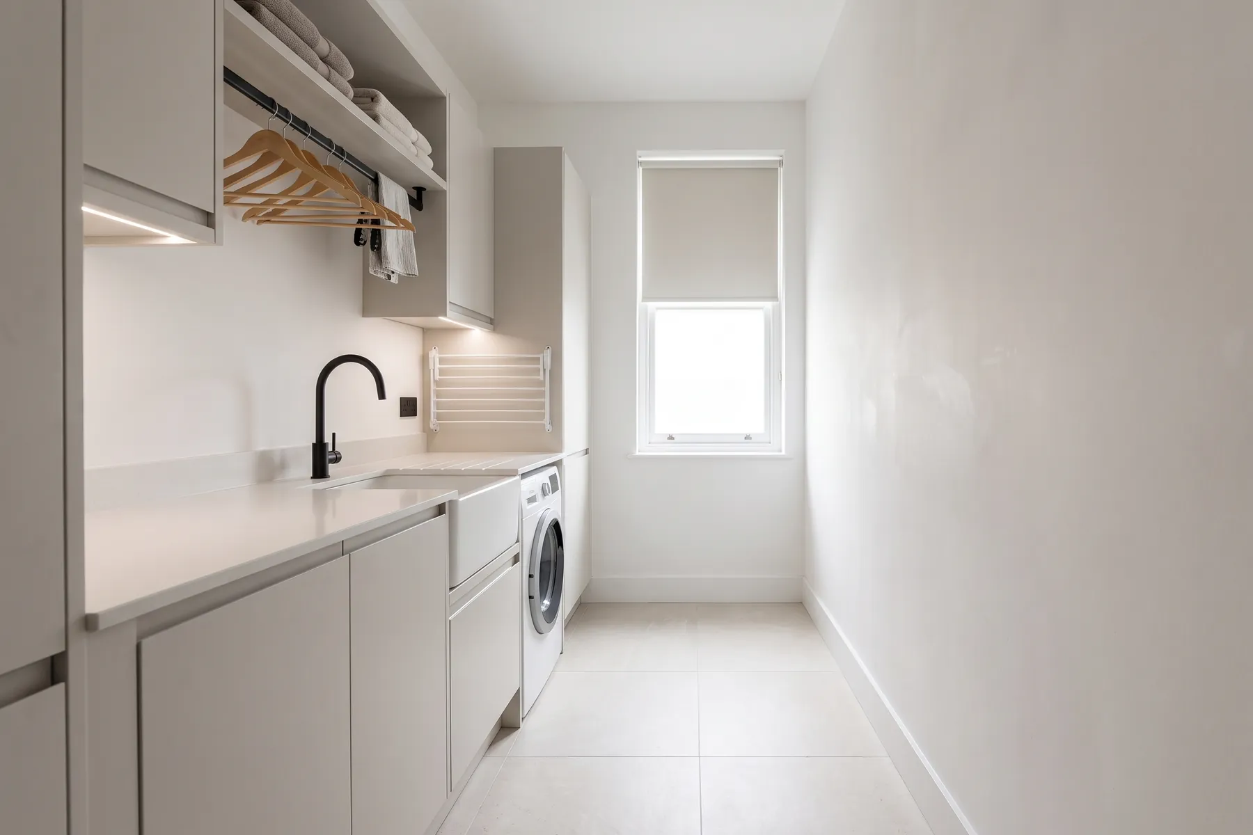 A NuaHome interior fitted out as a utility room, with a run of cabinets, a sink and hanging storage.